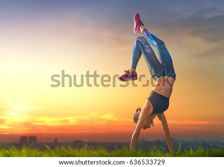 Healthy lifestyle and sport concepts. Woman in fashionable sportswear is doing exercise on nature. Girl on sunset background. 