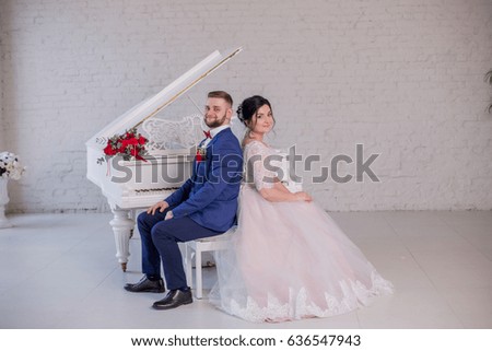 The bride and groom sit next to the piano