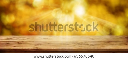 Gold glowing autumn background with empty wooden table for a concept