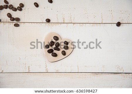 Coffee beans spread on Cartoon wooden heart. They are on white table.meaning who love to drink coffee,or who tell love someone.