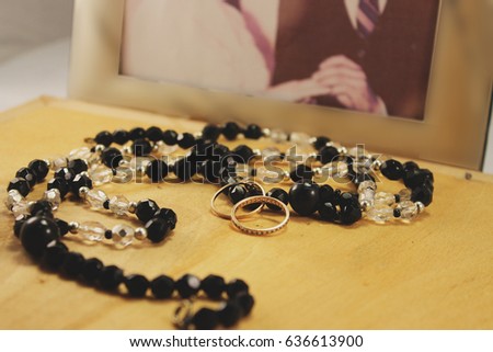 Touching memories of the wedding: on a wooden background vintage beads, rings and a photo that symbolizes the wedding procession and recalls memories