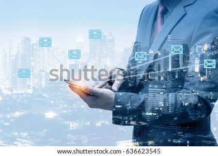 Double exposure of businessman sending E-mail by smart phone with city night background 