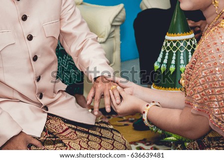 The bride puts a wedding ring on groom's finger, wedding in Thailand.
