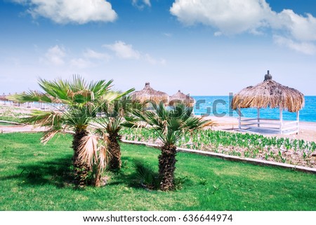Summer arbors on beach. Breathtaking view on mediterranean sea. White wooden summerhouses on sunny day. Blue sky and fluffy clouds