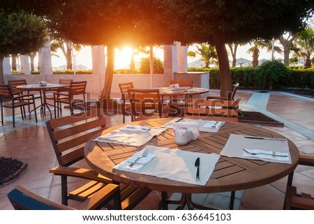 Summer restaurant on beach, near mediterranean sea. Wooden furniture and white napkin