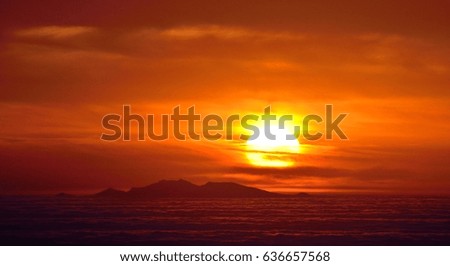 Distant island amidst sea of clouds at sunrise, Fuerteventura island