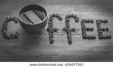 Coffee letters made of beans and cup on vintage boards. Black and white picture