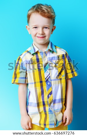 Portrait of a cute funny little boy looking at camera. Blue background. Copy space. Children fashion, summer concept.