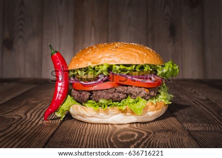 Classic burger and red pepper on wooden table.