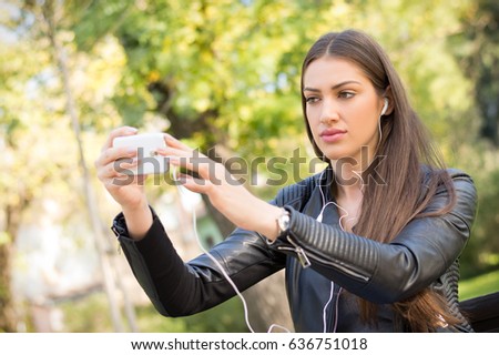 young beautiful girl doing selfie mobile phone in the park
