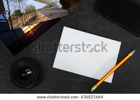 Blank paper on stone table with few postcards, phone and camera len
