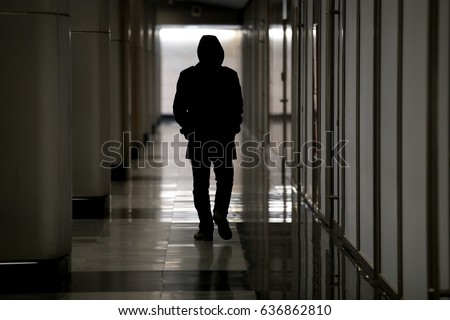 Unrecognizable male figure with hidden face in hood walking in dark hall, looking dangerous, stalking night robber burglar, bad troubled period, hooded guy feeling lost and abandoned, becoming ghost   Royalty-Free Stock Photo #636862810