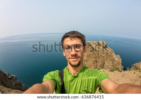 Man makes selfie on the rocks by the sea.