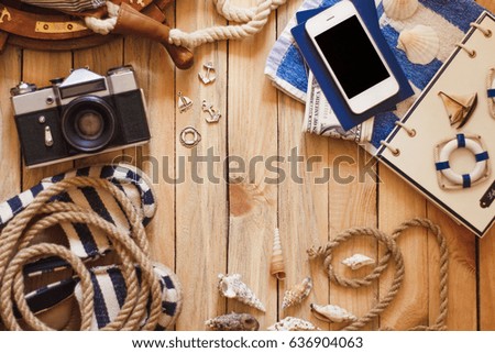 Striped slippers, camera, phone and maritime decorations on the wooden background, top view