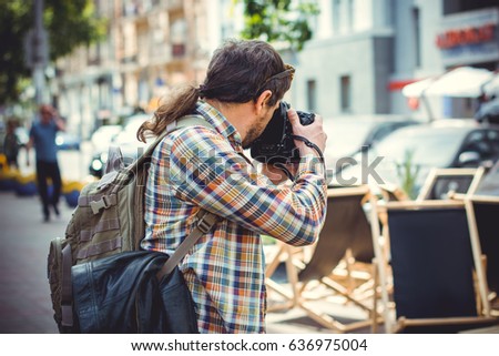 A man with a camera walks around the city photographing the neighborhood. The tourist came to see European sights and take a walk with a good mood