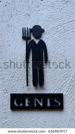 Man metal restroom sign on gray cement wall