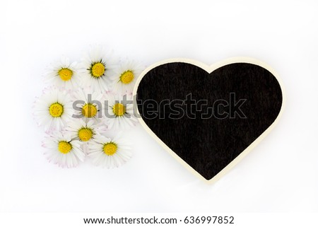 Daisies and a blackboard (heart-shaped) lying in front of white background