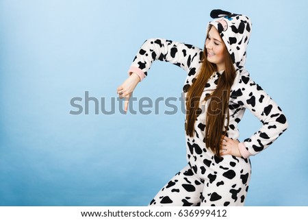 Happy teenage girl in funny nightclothes, pajamas cartoon style pointing down at copy space with positive face expression, studio shot on blue. Advertisement concept