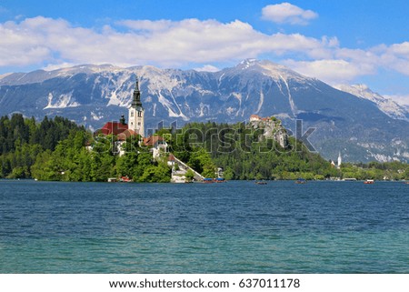 View of Lake Bled island with a small church and Julian alps in background