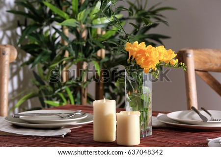 Beautiful festive table setting and vase with flowers in light room
