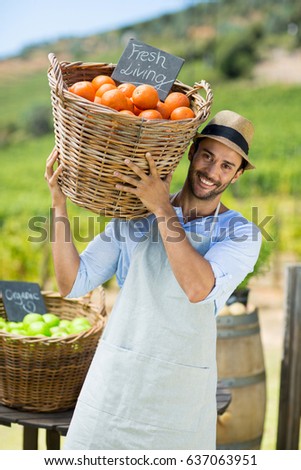 Portrait of happy farmer carrying by fresh oranges in container at farm market for sale