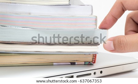 Stack of books on laptop with hand