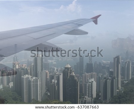 The concept of traveling to Hong Kong with passenger plane .The airplane wing with Hong Kong island background, view from Victoria peak.