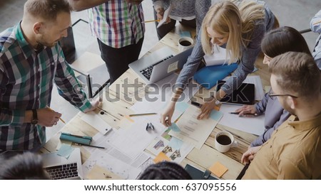 Top view of mixed race group of people standing near the table. Young business team working on start-up project together Royalty-Free Stock Photo #637095556