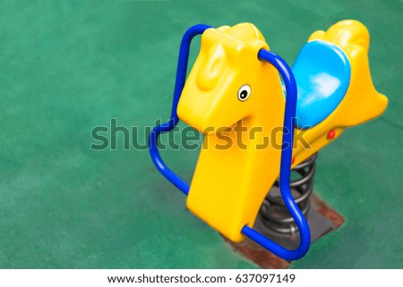 Bright colorful toy horse in a green playground on sun light.