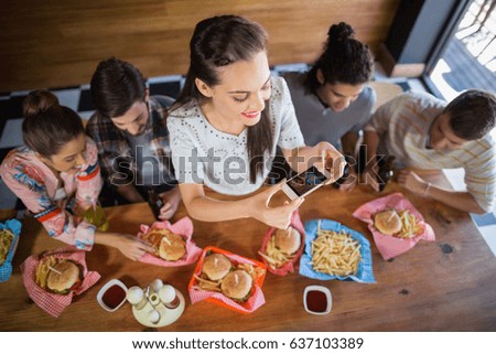 High angle portrait young woman with friends photographing food in restaurant