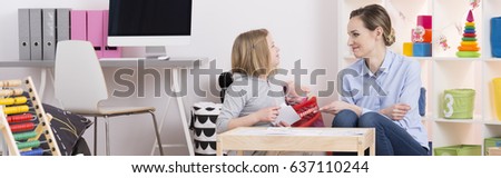 Young teacher helping little girl with her homework