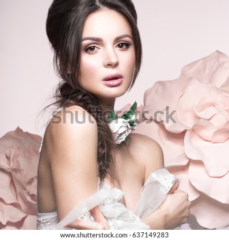 Beautiful girl with classic make-up and hairstyle in delicate Underwear with large flowers on background. beauty face. Photos shot in studio