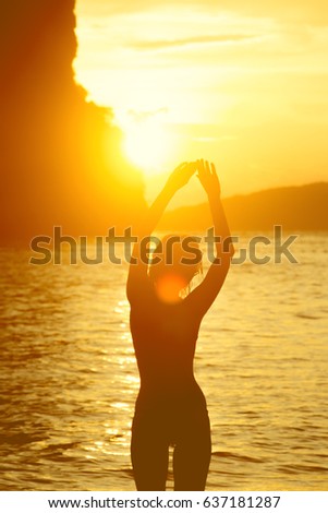 female body silhouette against bright sea sunset and sunny islands on horizon line
