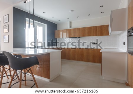 Contemporary kitchen in classical style with loft details. Luxury apartment downtown. Dining zone in comfortable brand new apartment. Black loft style chairs. Loft style table. Brick wall. 