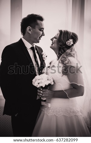 Black white photography  bride and groom posing in a hotel room on background windows