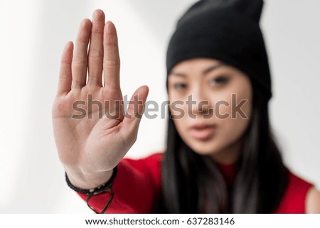 portrait of attractive asian woman showing stop sign isolated on grey