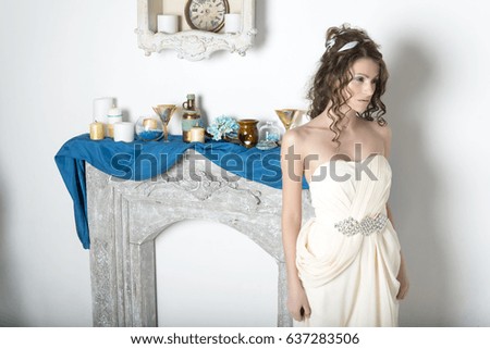 Girl in white near the decorative fireplace in the room.
