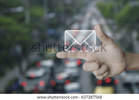 Mail icon on finger over blur of rush hour with cars and road, Contact us concept