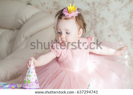 Portrait of a small beautiful girl in a crown and a pink elegant dress on a holiday