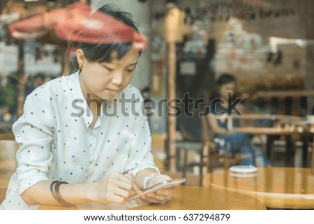 Asian woman playing smarphone in coffee shop.