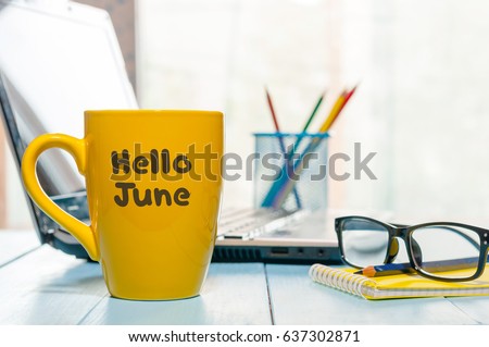 Hello June - inscription at yellow morning coffee or tea cup at business office background. First summer day, Calendar concept Royalty-Free Stock Photo #637302871