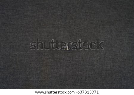 A high resolution of black cloth texture with a little white thread art in a middle.
