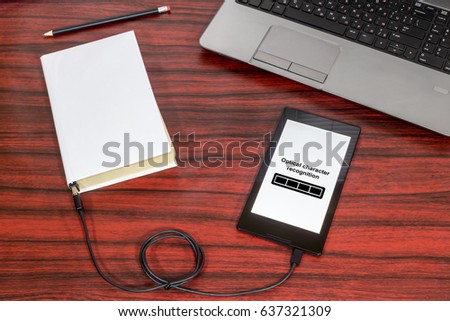 Book connected to a tablet through an USB cable on a desk. Optical character recognition loading bar.