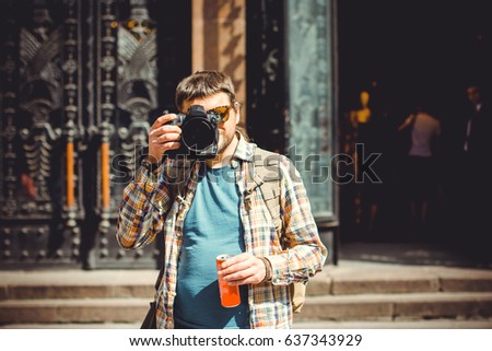 A man with a camera walks around the city photographing the neighborhood. The tourist came to see European sights and take a walk with a good mood