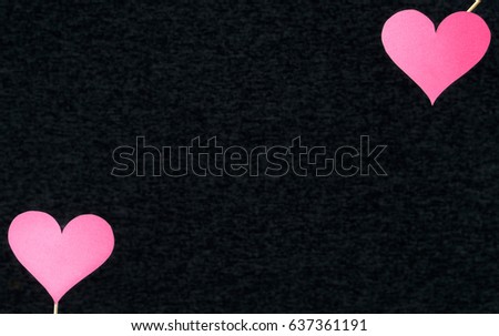Dark heart background with free empty blank copy space for text or quote. Two red classic love shapes cut from cardboard or paper on wooden sticks in the corner. Gray or black texture backdrop.