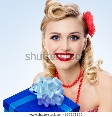 Portrait of beautiful young happy smiling woman in pin-up style clothing, on blue background. Caucasian blond model posing in retro fashion and vintage concept studio shoot.