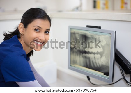 Closeup portrait of allied health dental professional in blue scrubs examining dental x-ray on computer screen, isolated dentist office Royalty-Free Stock Photo #637390954