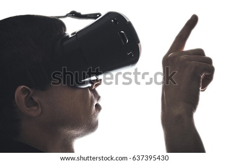 Portrait of a profile of a young man in virtual reality glasses showing by finger on a white isolated background