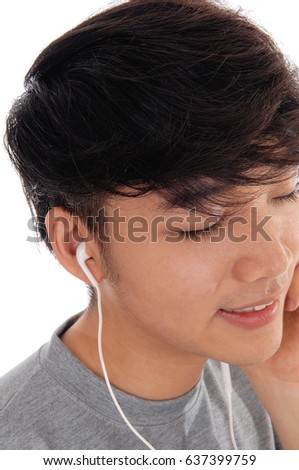 A closeup image of the face of a Asian teenager listening to the music
from his cell phone, eyes closed, isolated for white background.
