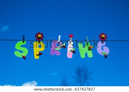 Inscription spring with colorful letters on clothespins on blue sky background